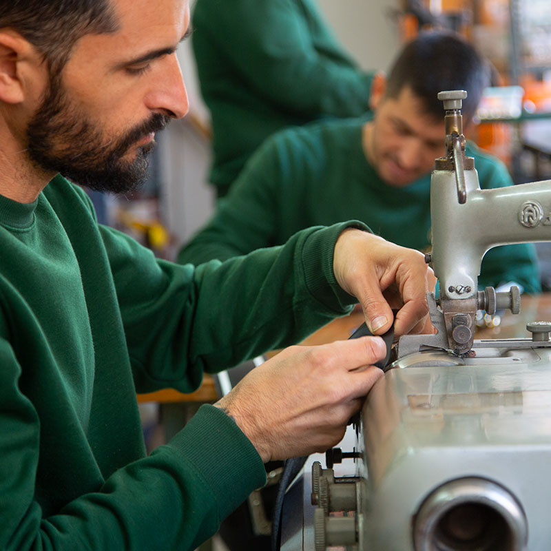 Hombre trabajando en una máquina de coser en fábrica de calzado