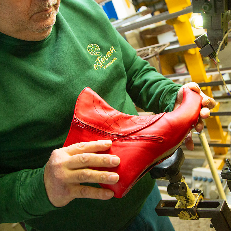 Un hombre con un zapato estilo moro de color rojo en las manos